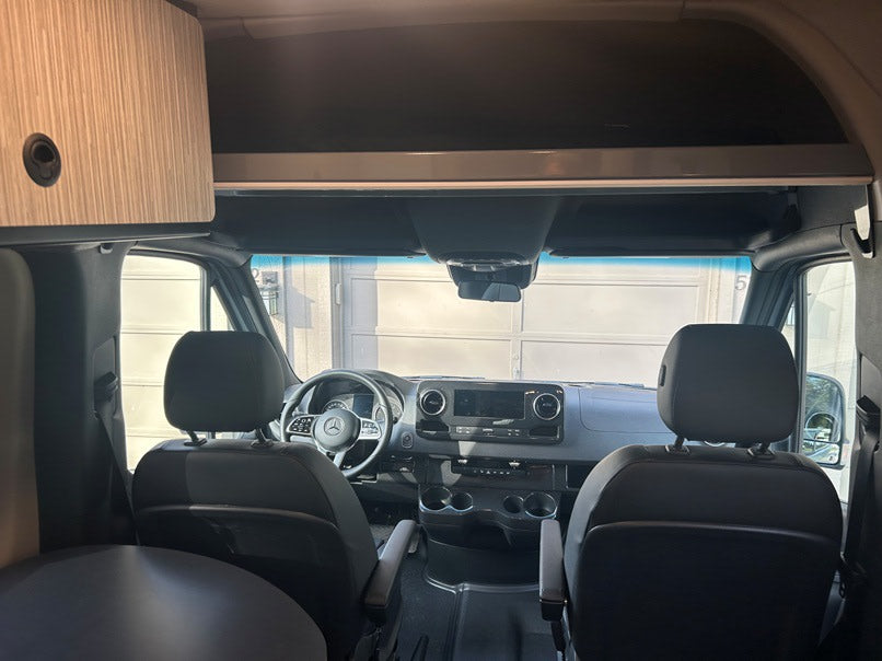 Spacious rv rental interior: Looking into the modern cockpit with front seats, steering wheel, and dashboard.