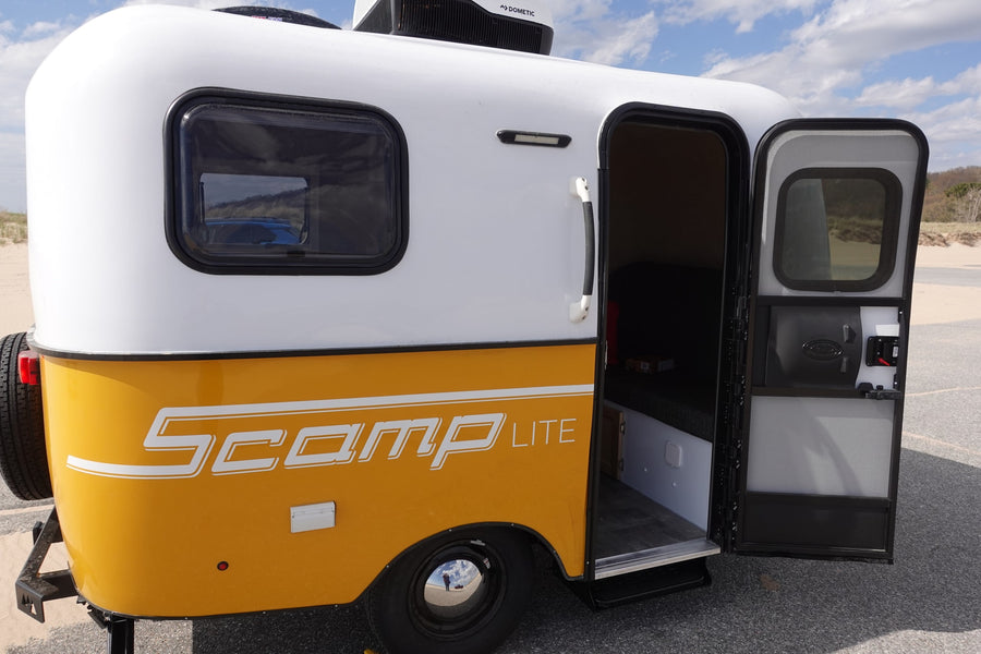 Yellow and white Scamp Lite compact travel trailer, an ideal rv rental. Door open for outdoor adventures.