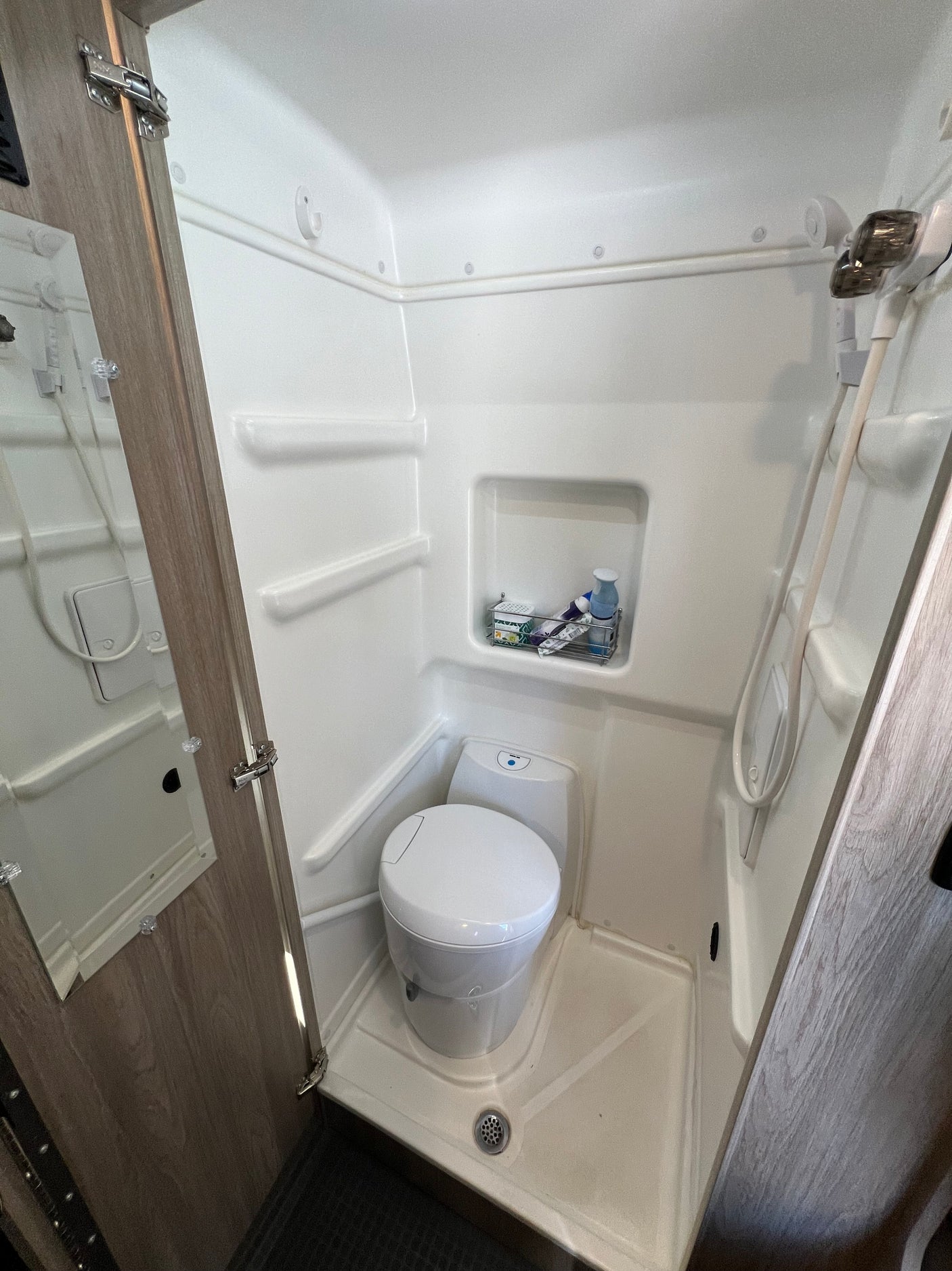 Compact RV rental wet bath with toilet, shower, and mirror, perfect for small spaces.