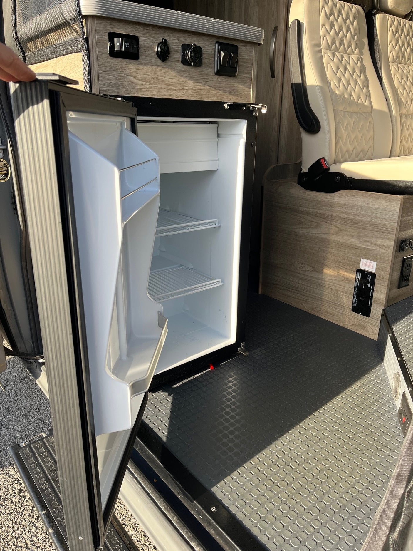 RV rental camper van interior. Features an open mini-fridge, kitchen controls, and stylish quilted seating for your travels.