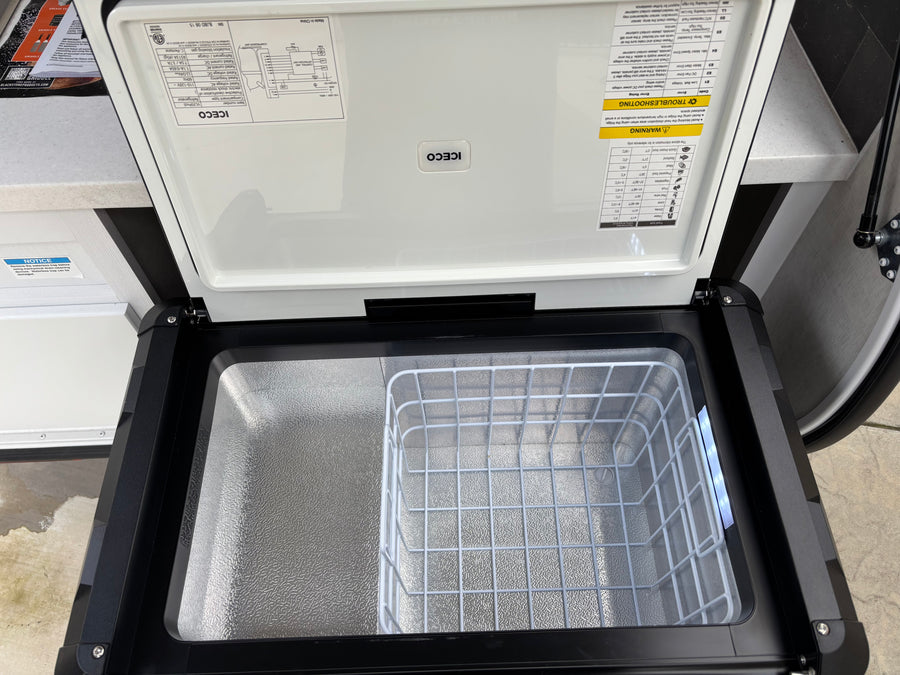 Open ICECO portable fridge/freezer for your rv rental. Interior shows a wire basket and product info on the lid.