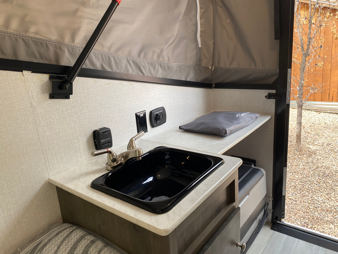 RV rental interior: compact kitchen with sink, faucet, thermostat, outlets, and charging center in a pop-up camper.