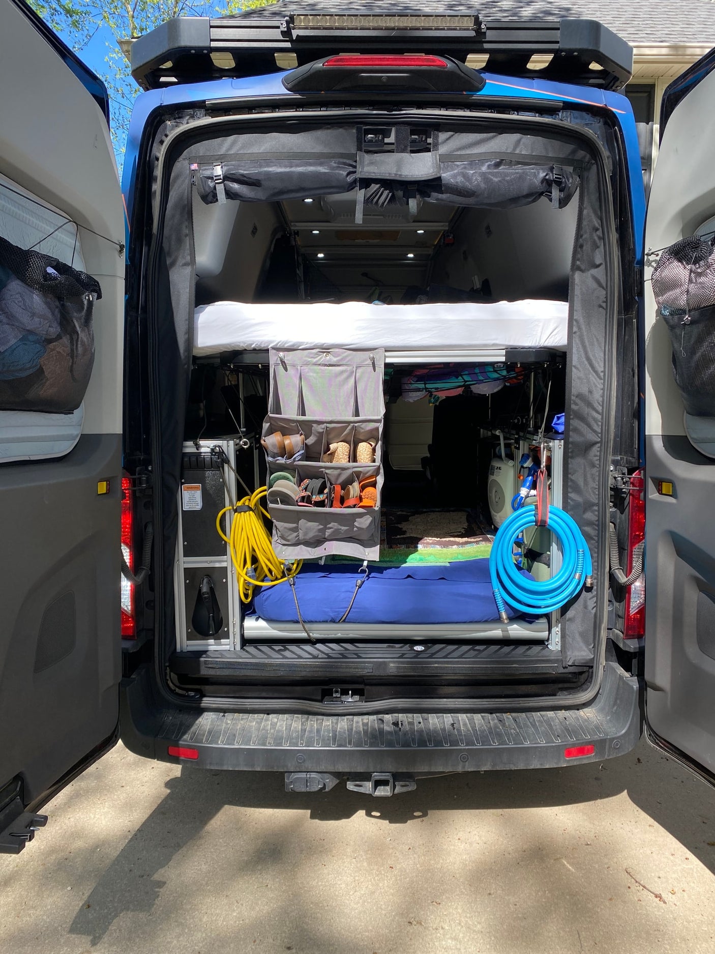 Detailed view of a camper van's organized rear. Perfect for your RV rental, showing bed, storage, and utility connections.