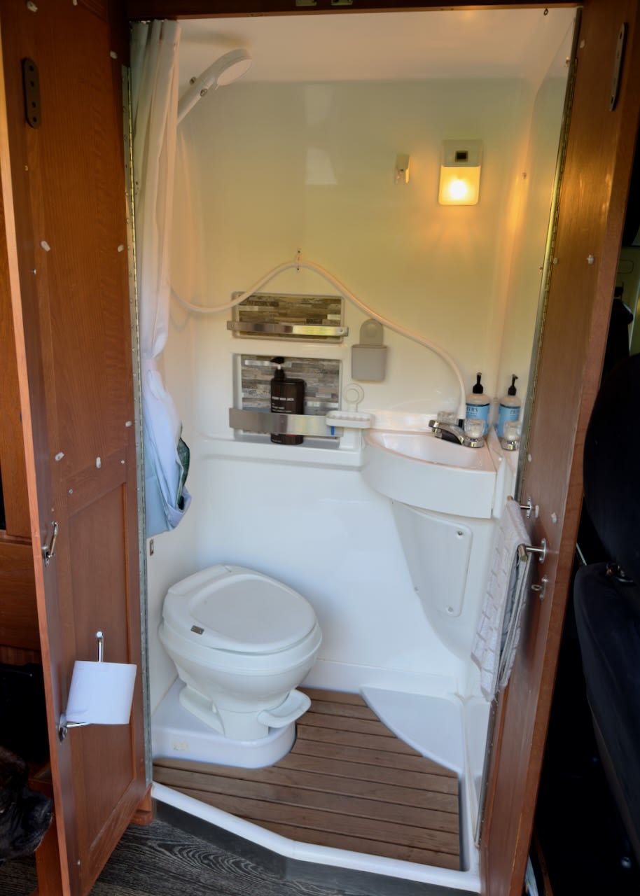 Compact RV rental bathroom with toilet, sink, and shower. Essential amenities visible for a comfortable trip.