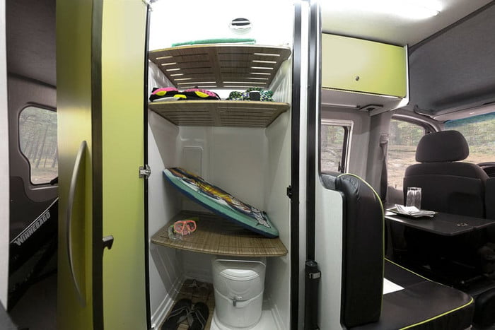 Compact rv rental interior showing organized storage for gear like a boogie board, PFDs, and a portable toilet, plus dinette seating.