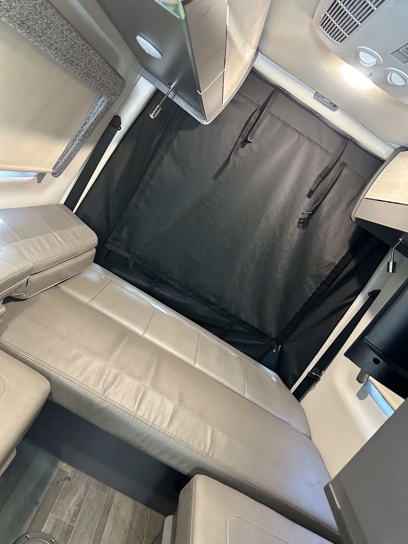 Inside an RV rental: A light-colored bench seat and dark privacy curtain offer comfort & shade for travel.