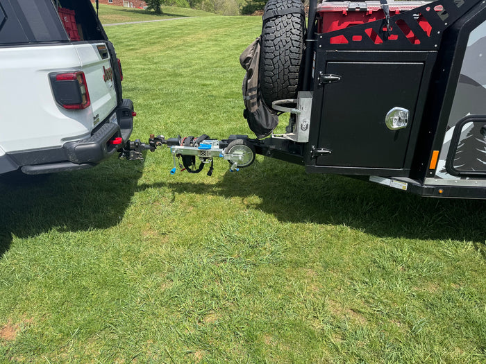 White Jeep truck hitched to an off-road trailer with a bike rack. Ideal setup for an RV rental adventure.