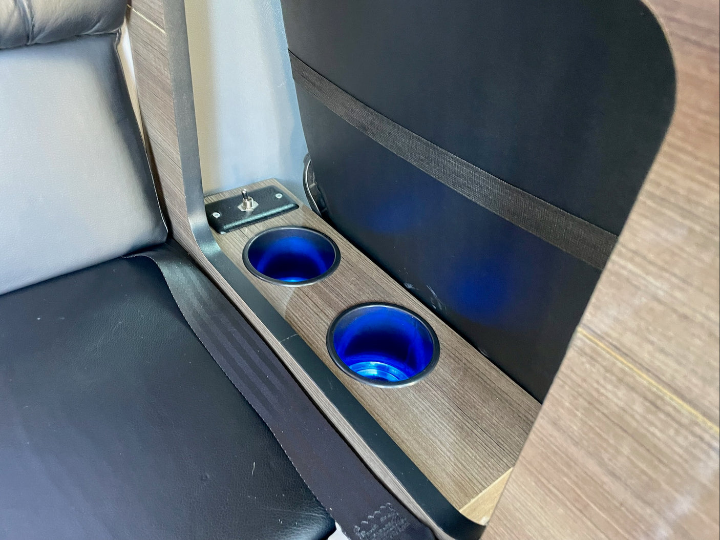 RV rental interior shows a console with two blue LED-lit cup holders, a toggle switch, and a seat with a seatbelt.