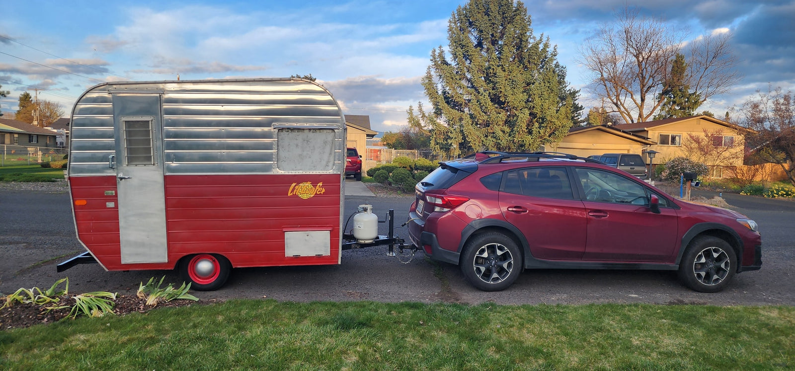 Red Subaru towing a vintage "Little Loafer" travel trailer