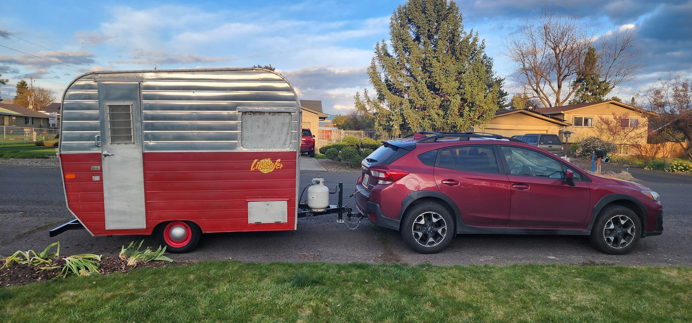 Red Subaru towing a vintage "Little Loafer" travel trailer