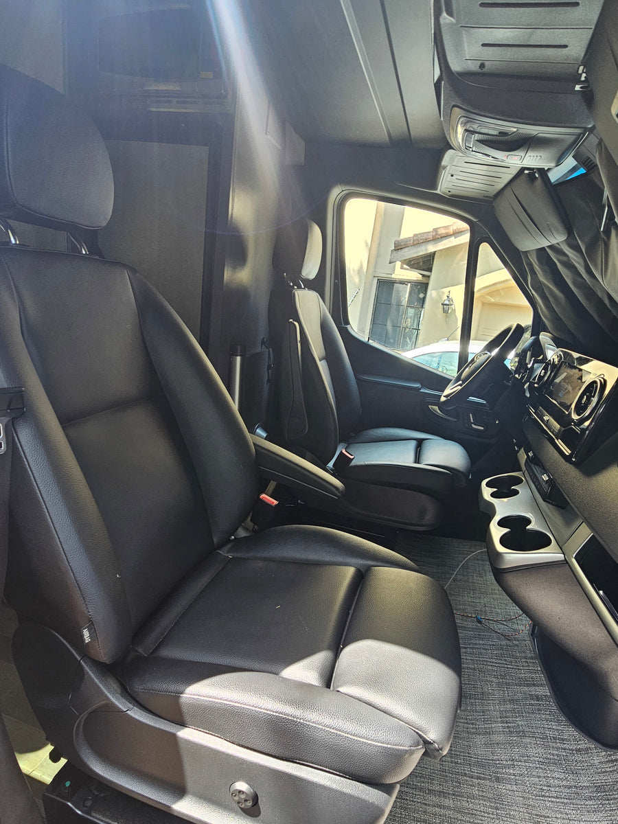 Spacious RV rental interior featuring black leather seats, dashboard, and living area amenities.