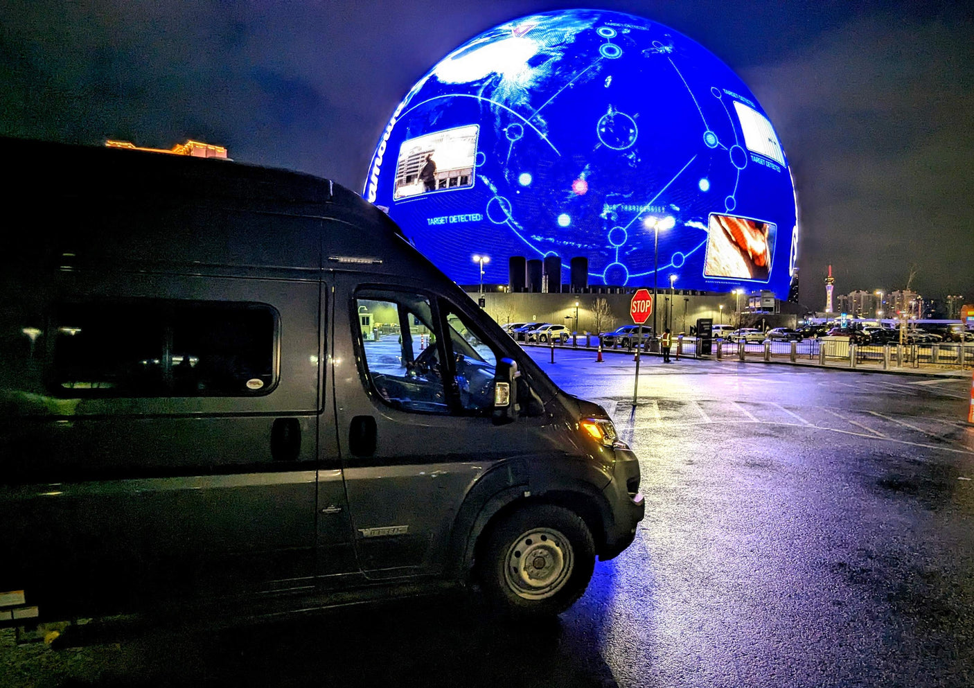 Night view of an RV rental in Las Vegas with The Sphere displaying "TARGET DETECTED." Unique travel experience.