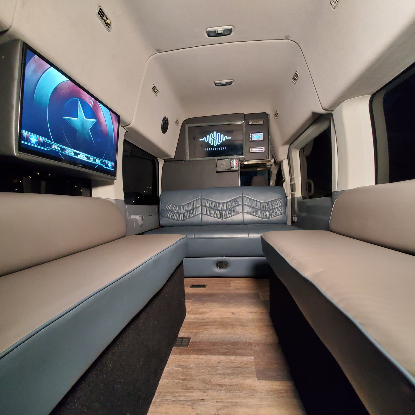 Spacious RV rental interior with comfortable seating, a large entertainment screen showing Captain America, and modern controls.