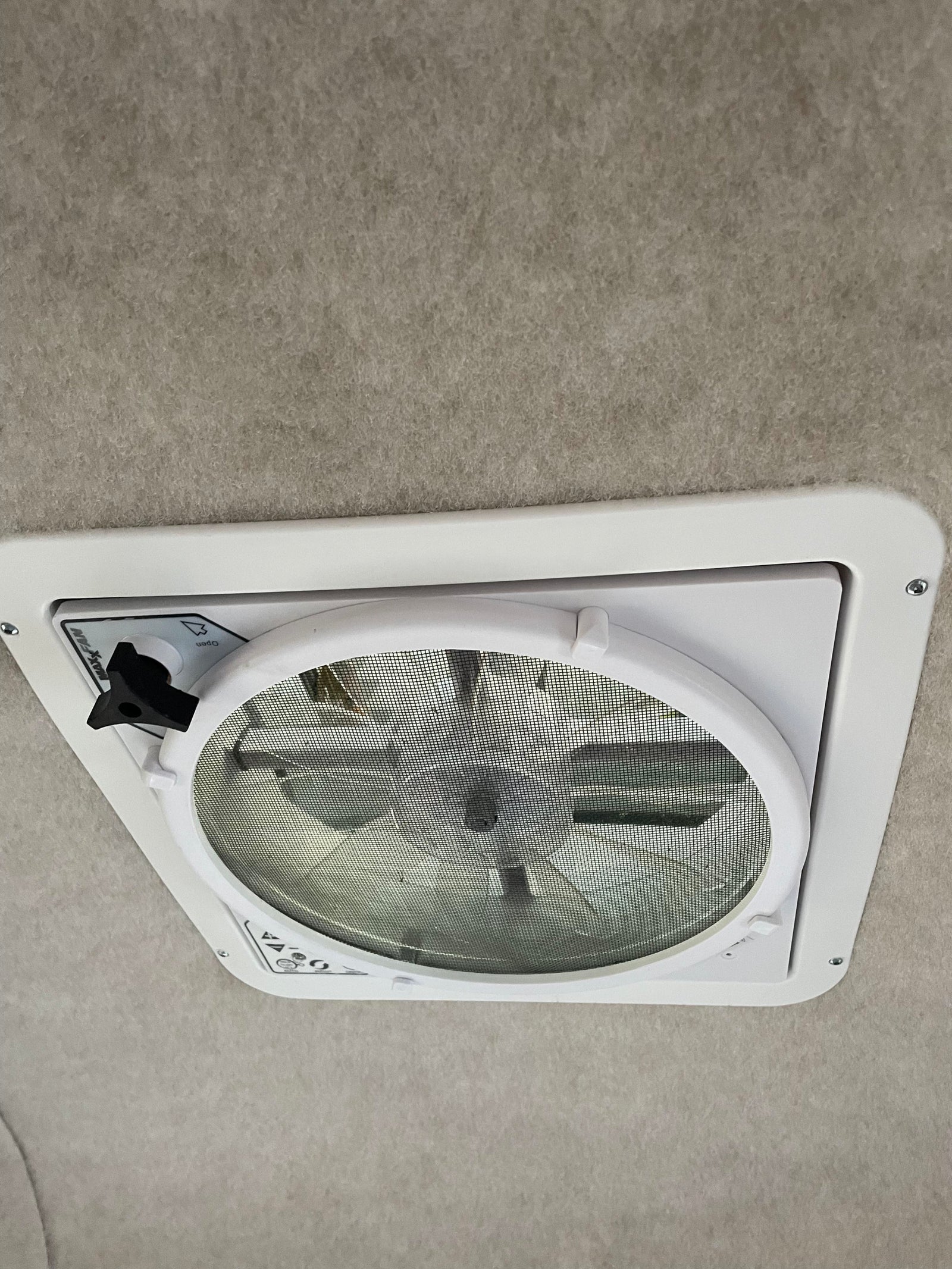 An RV rental features a Maxx-Fan ceiling vent with screen, offering fresh air. Light grey upholstered interior.