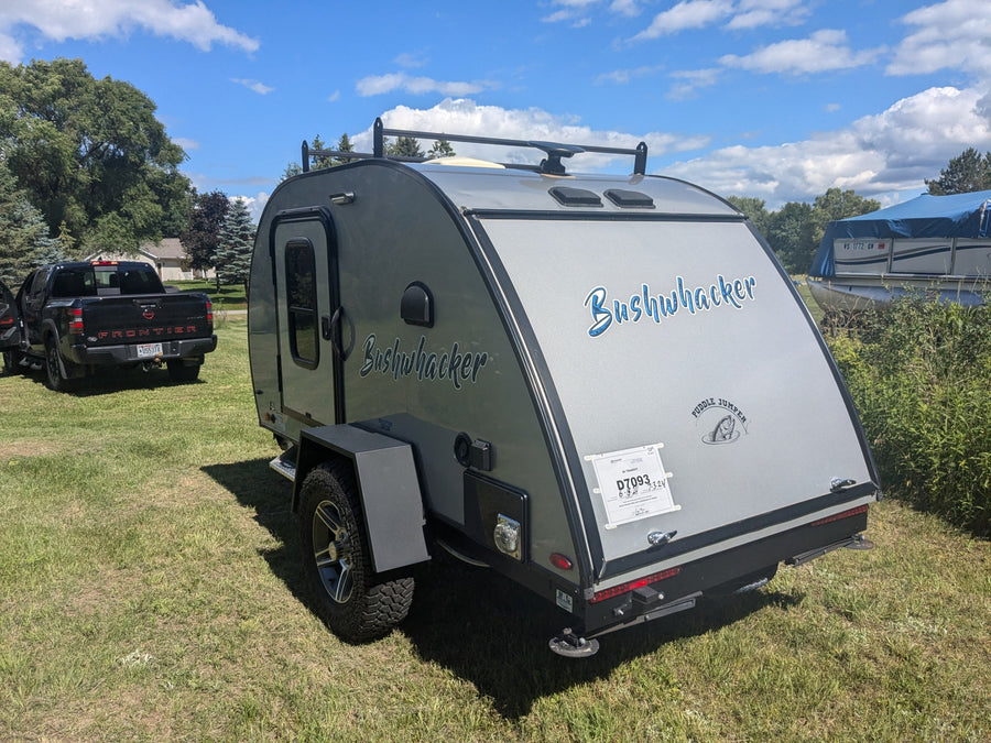 featuring an open outdoor kitchen at a serene campsite.|Gray Bushwhacker teardrop RV trailer