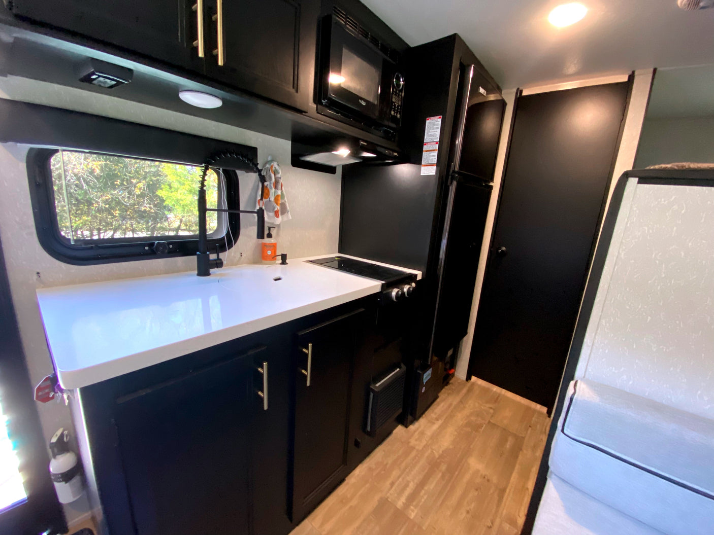 Modern RV rental kitchen with black cabinets, white counters, and essential appliances for travel comfort.