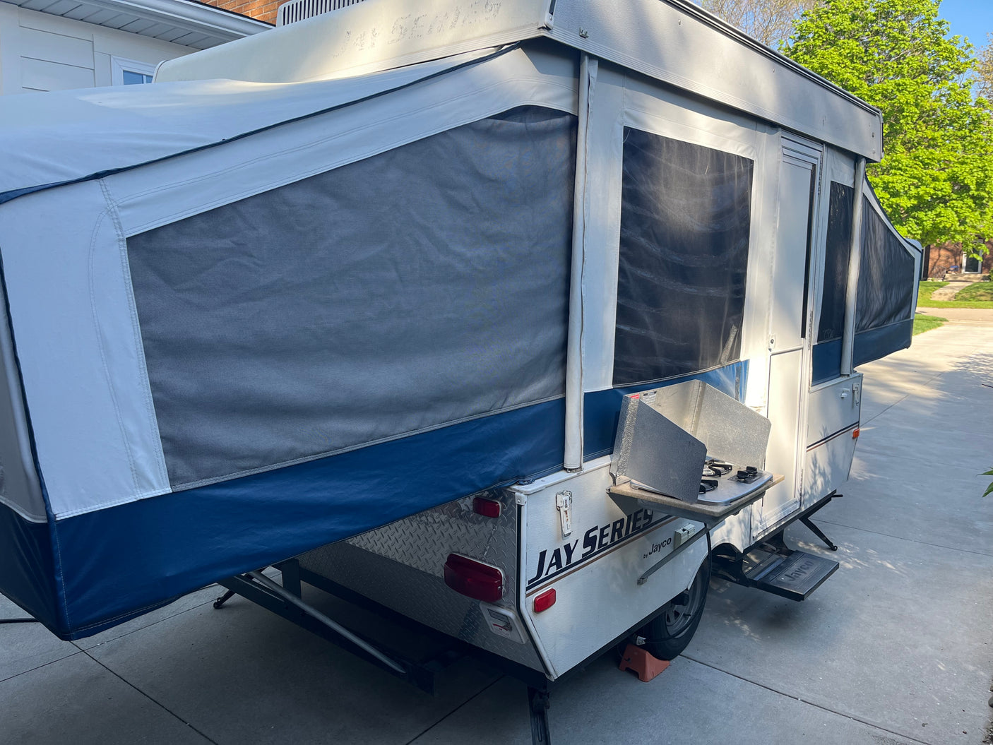 This Jayco pop-up RV camper, fully extended with an outdoor stove, offers compact comfort for your next RV rental trip or camping adventure.