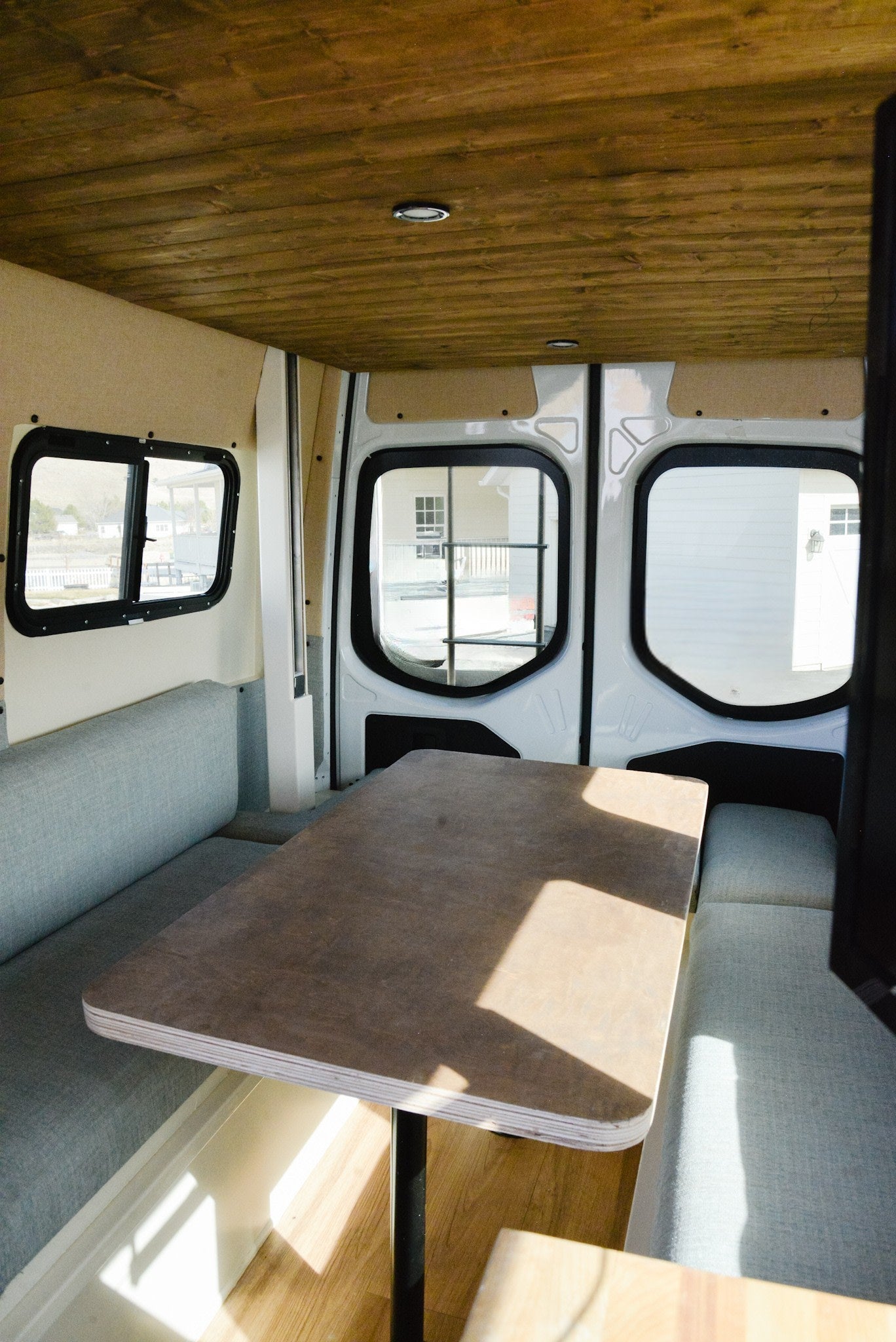 RV rental interior with a cozy dinette, light benches, a wooden table, and plank ceiling. Perfect for trips!