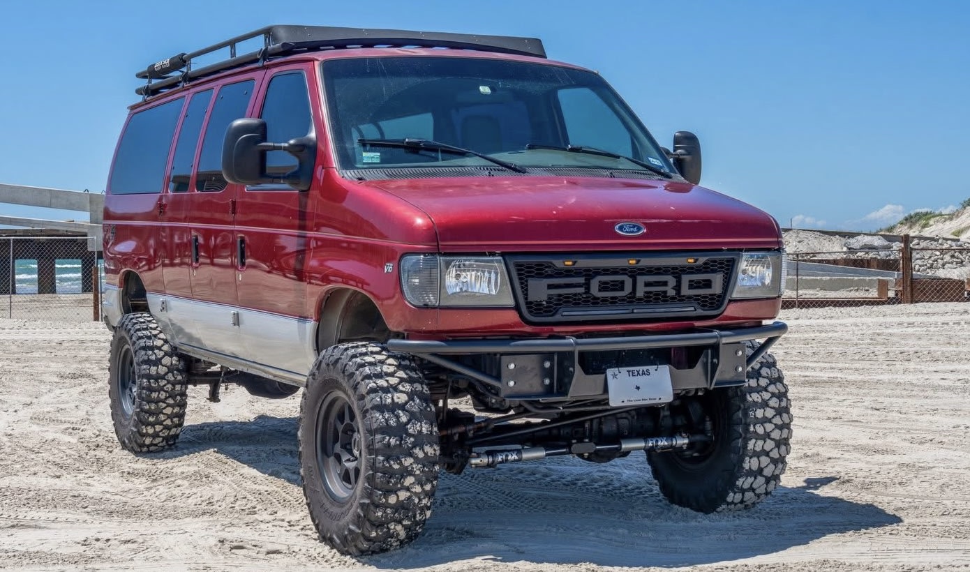 This red lifted Ford E-Series off-road van on a sandy beach — photo 1