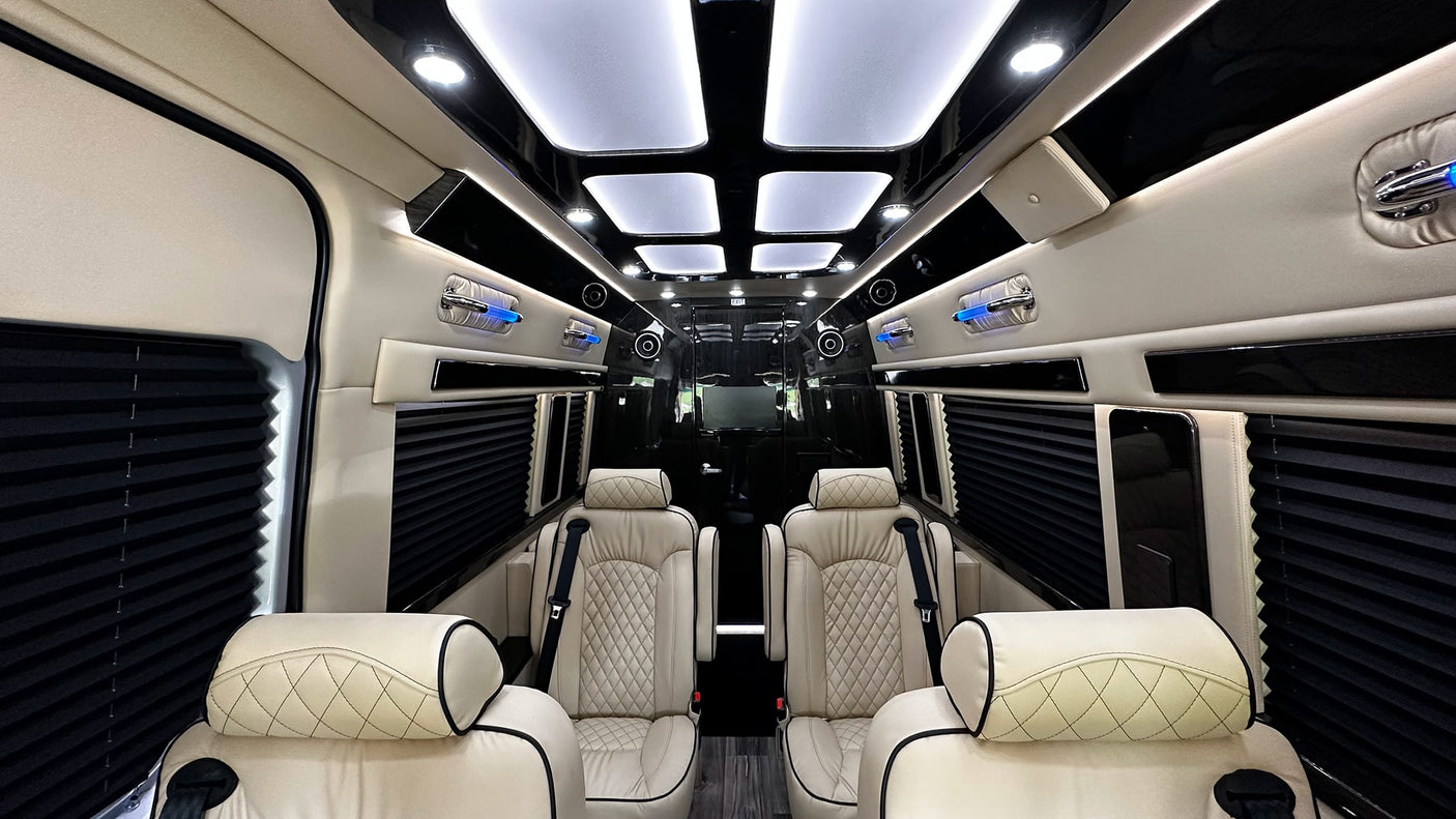 Inside a spacious RV rental, cream quilted leather seats, black window shades, and bright ceiling lights create a luxury travel experience.