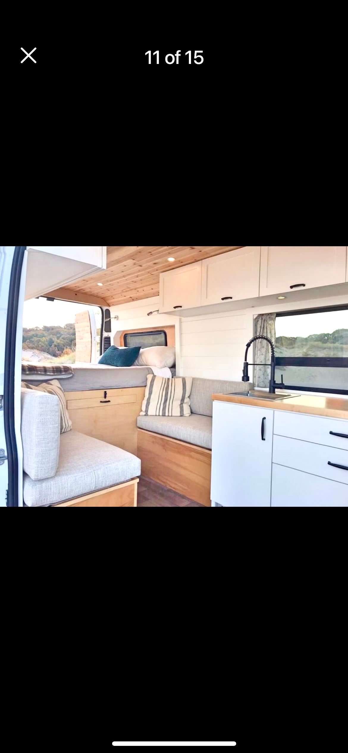 Modern RV rental interior: kitchen, bed, & spacious living area in a camper van.