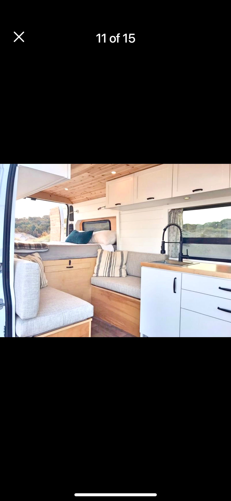 Modern RV rental interior: kitchen, bed, & spacious living area in a camper van.