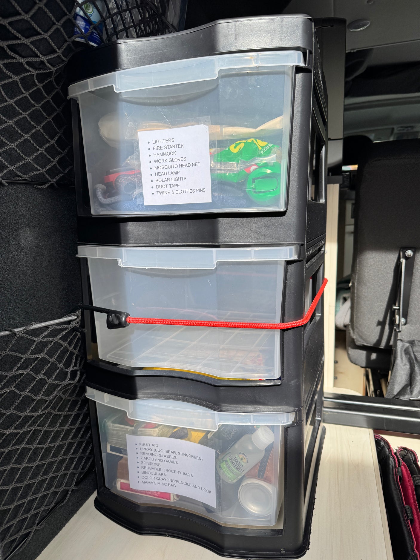 Inside an RV rental: stacked clear drawers neatly organize camping, first aid, and travel essentials with labels.