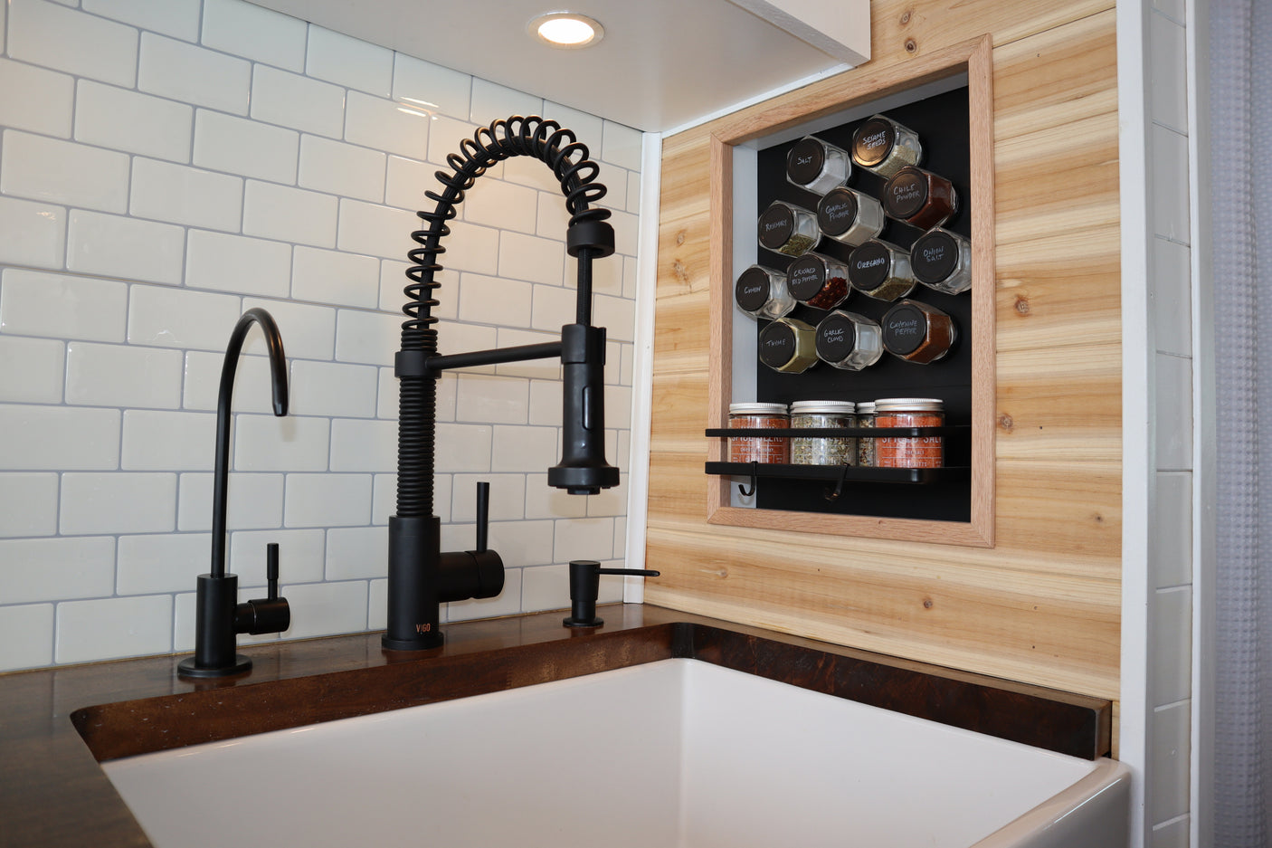 Modern RV rental kitchen with a sleek black faucet, white subway tile, and a clever built-in magnetic spice rack.