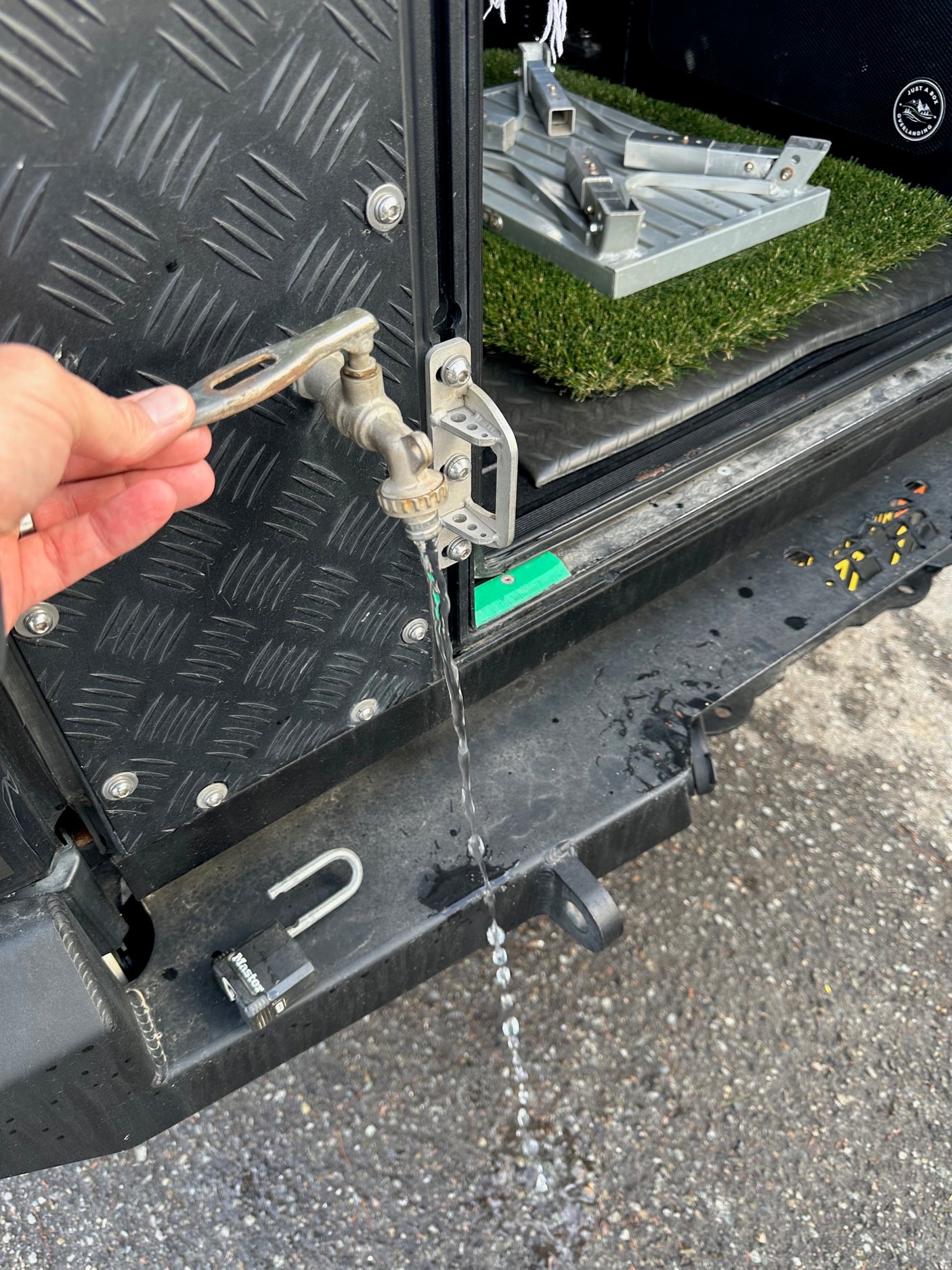 Water streams from a portable spigot on this overland RV rental setup, perfect for outdoor utility and refreshing adventures.