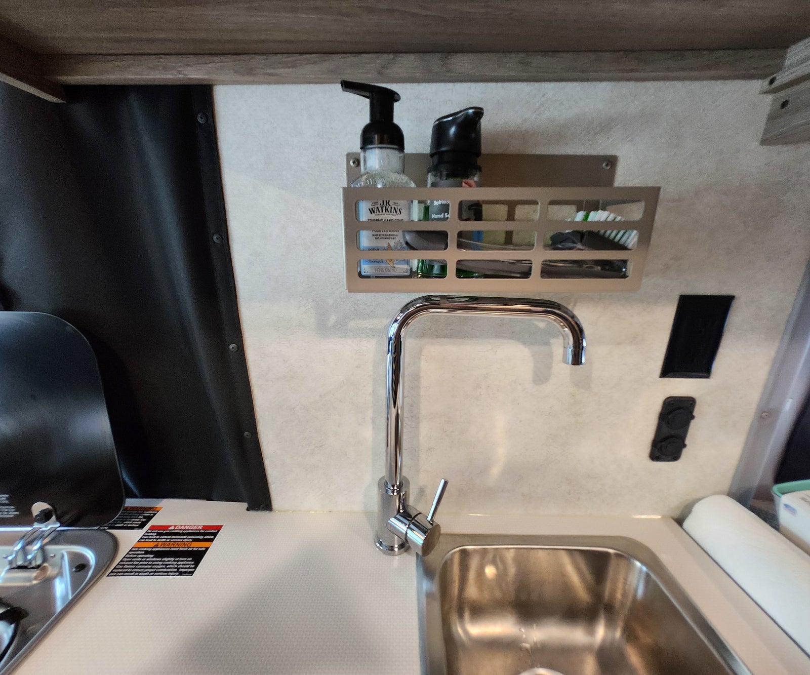 and a rear bed.|Modern RV rental interior: compact camper van features a convertible bed