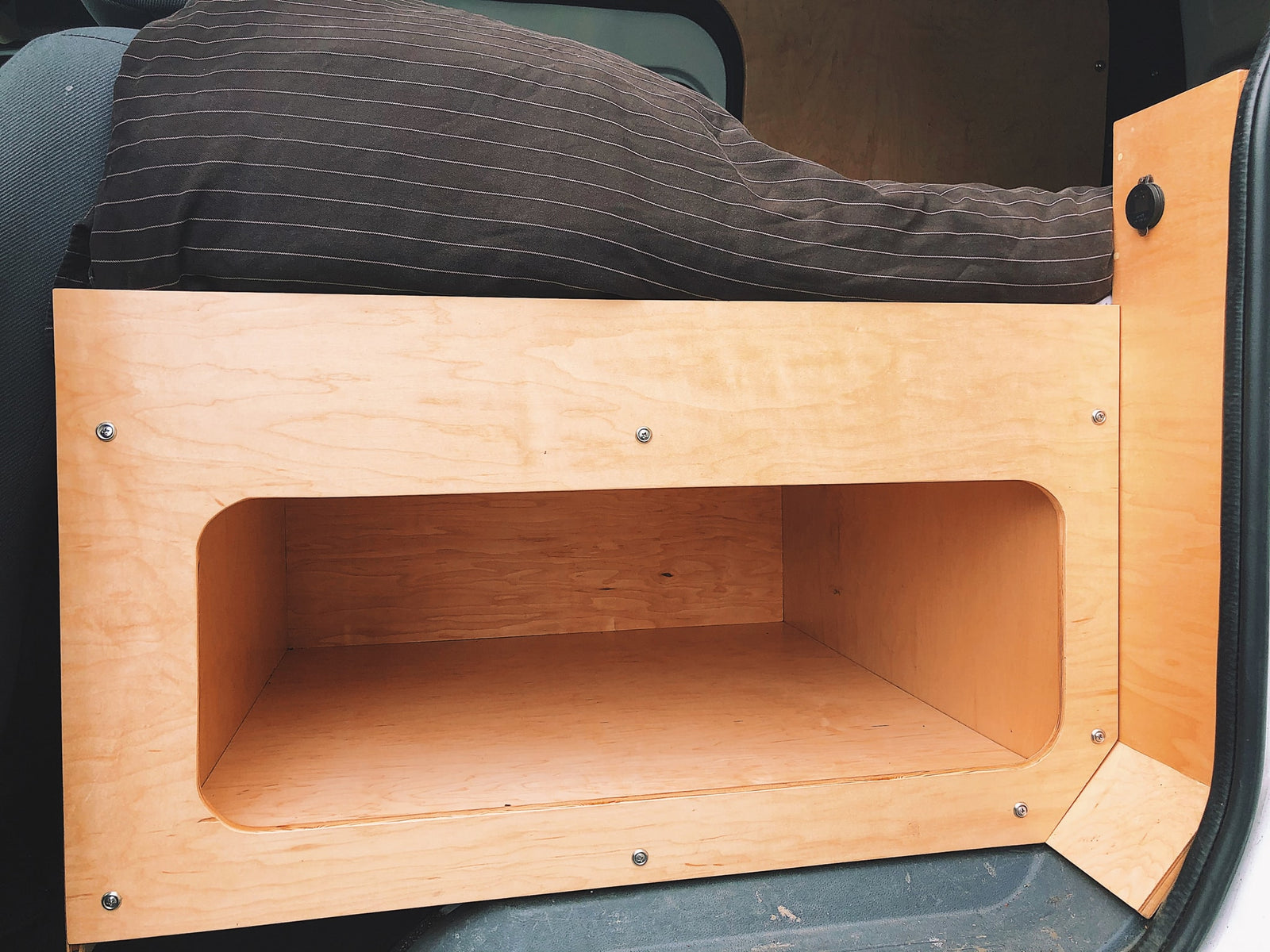 wood-paneled bedroom opening to a serene lake and mountain view.|Inside an RV rental: a portable power station (1500W) on a pull-out tray