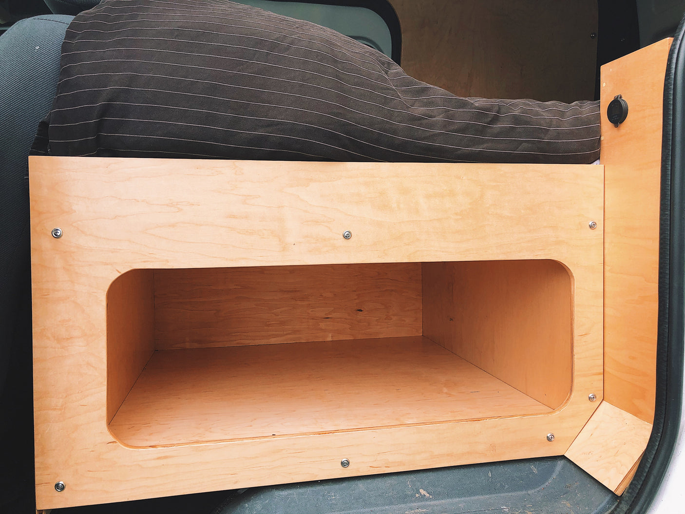 wood-paneled bedroom opening to a serene lake and mountain view.|Inside an RV rental: a portable power station (1500W) on a pull-out tray