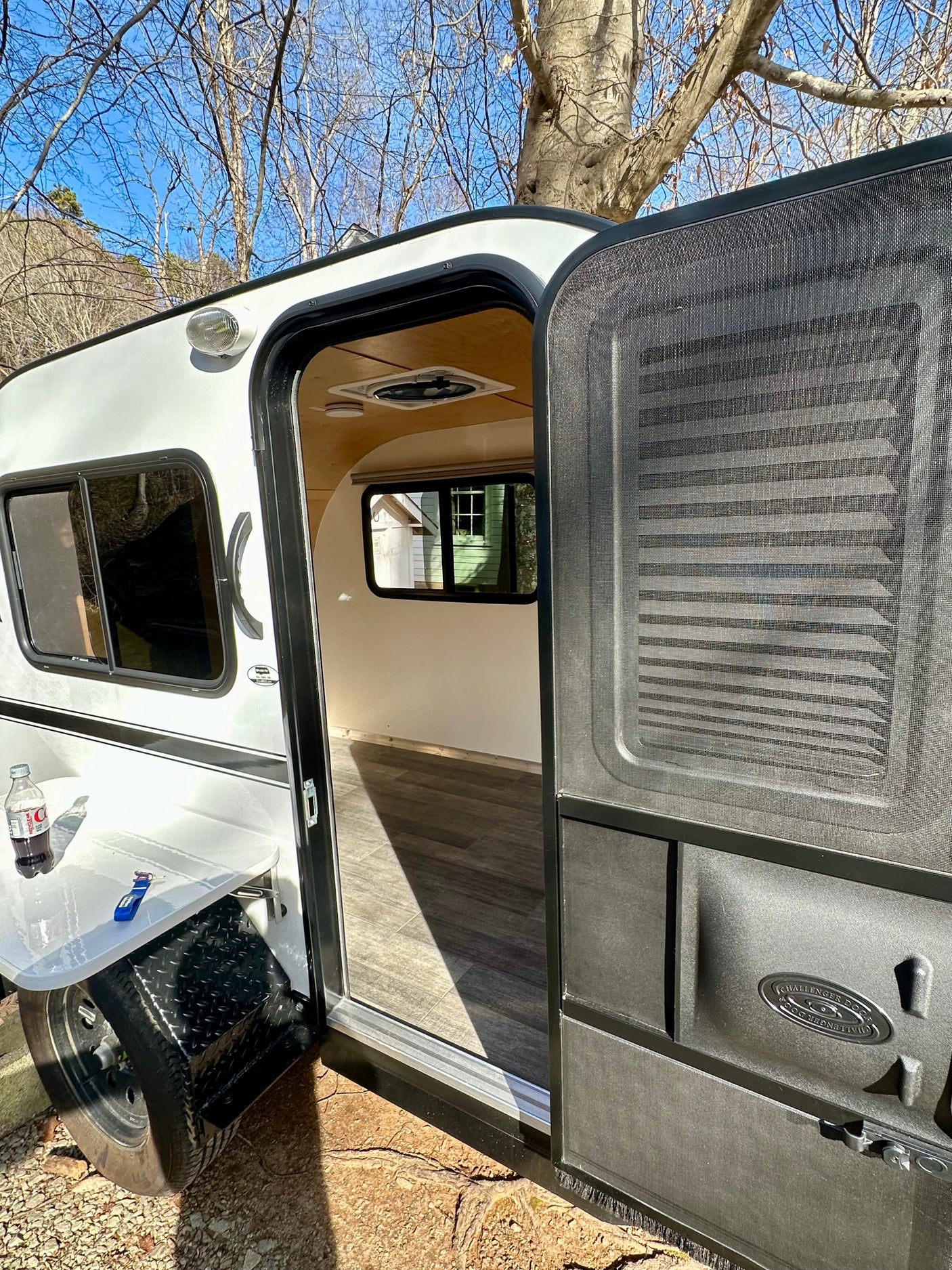 White teardrop camper rv rental with open door showing wood floor interior.
