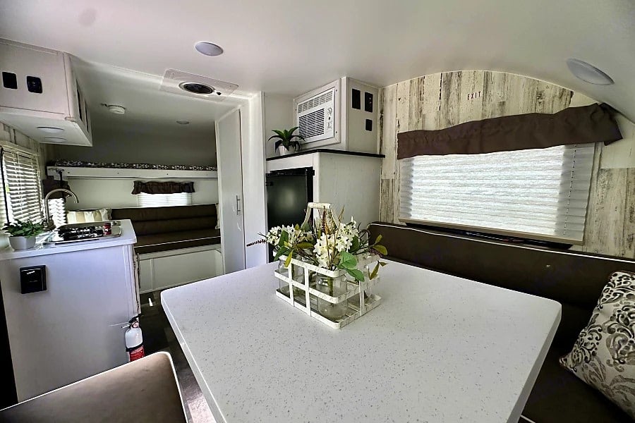 and dinette seating for comfortable travels.|Cozy RV rental bedroom with patterned bedding — photo 7