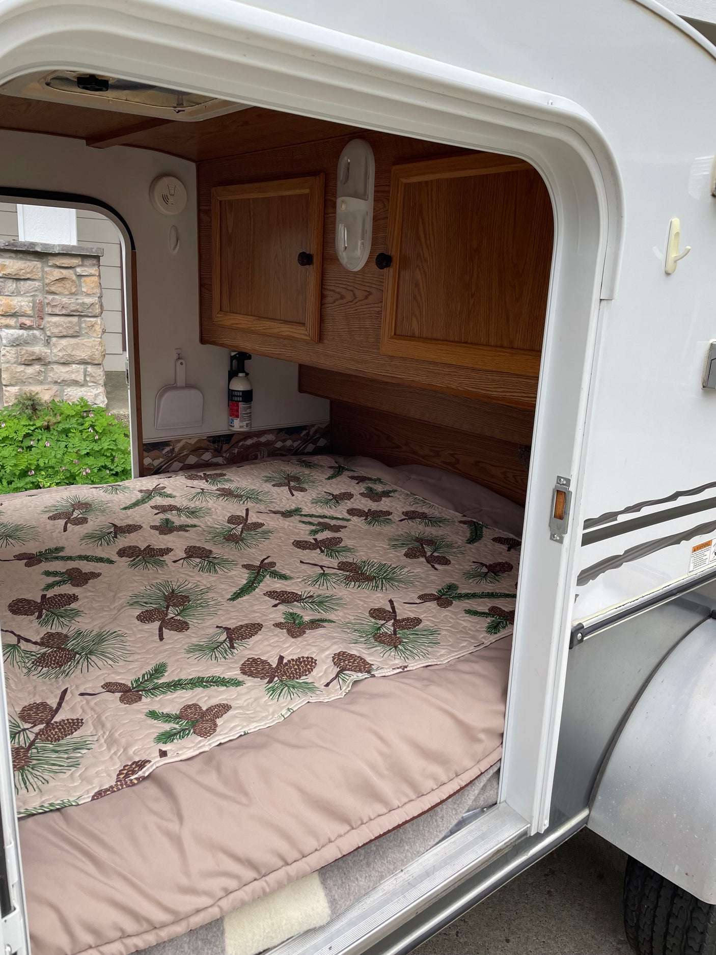perfect for an RV rental. Parked in a driveway by a house with flowers.|Step inside this cozy RV rental camper