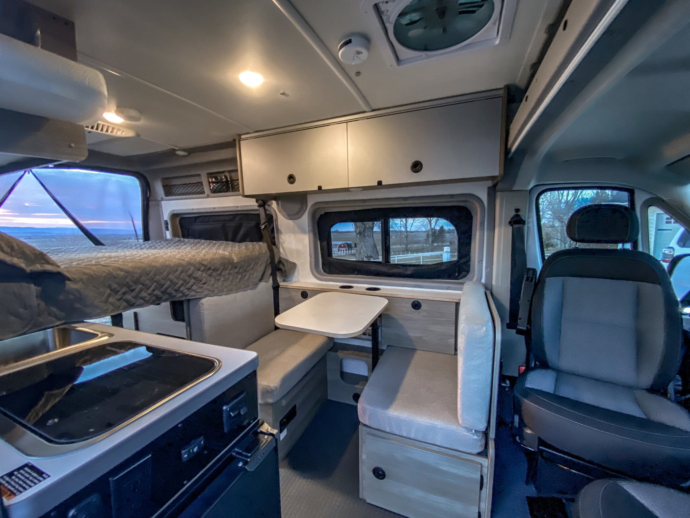 An RV rental's well-designed interior features a bed, kitchen, dining area, and overhead storage.