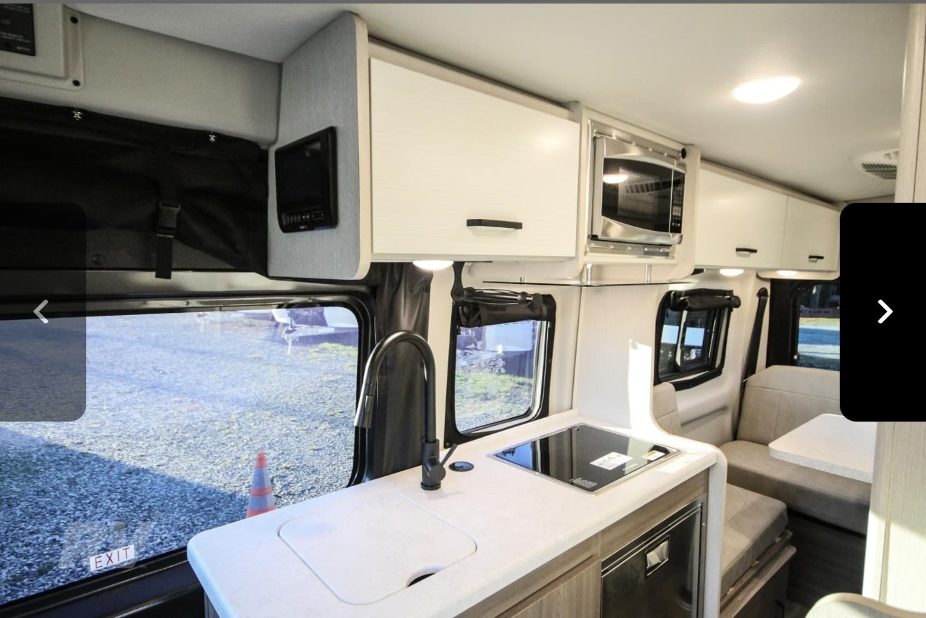 and swivel chairs with tables.|Rear view of an RV rental with open doors — photo 3