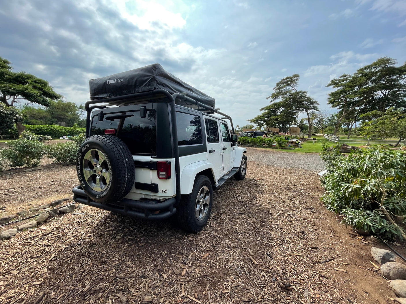 White Jeep Wrangler with Thule Tepui roof-top tent, a compact RV rental ready for outdoor adventures.
