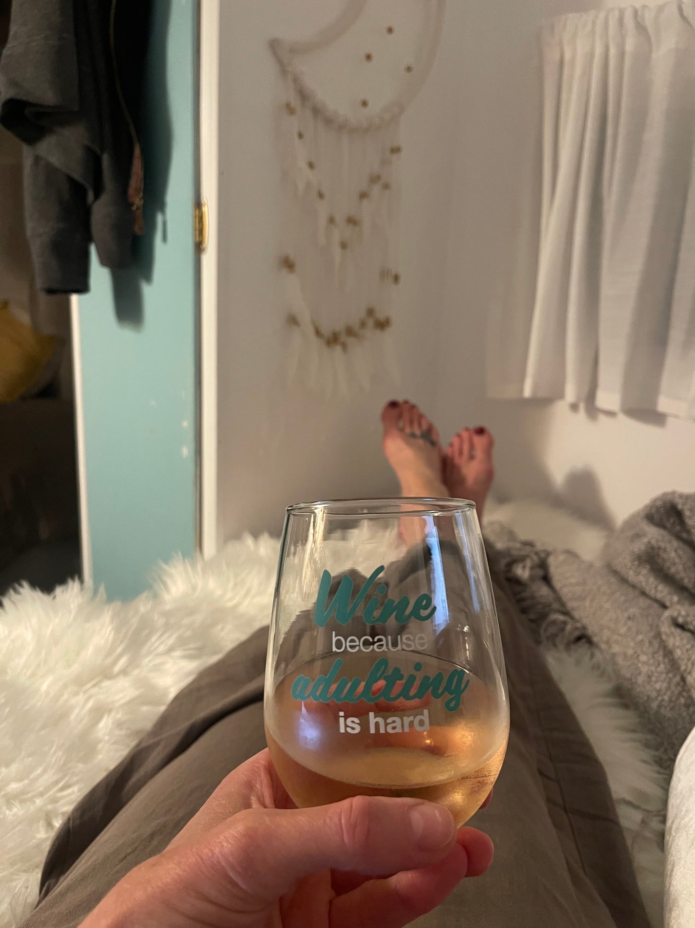 Cozy RV rental evening. Relaxing with feet up, holding a wine glass that reads "adulting is hard."