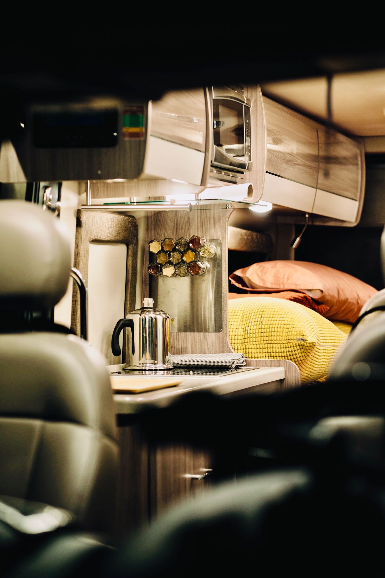 and natural light from overhead and side windows.|Cozy RV rental interior: a colorful bed next to a compact wet bath with toilet — photo 20