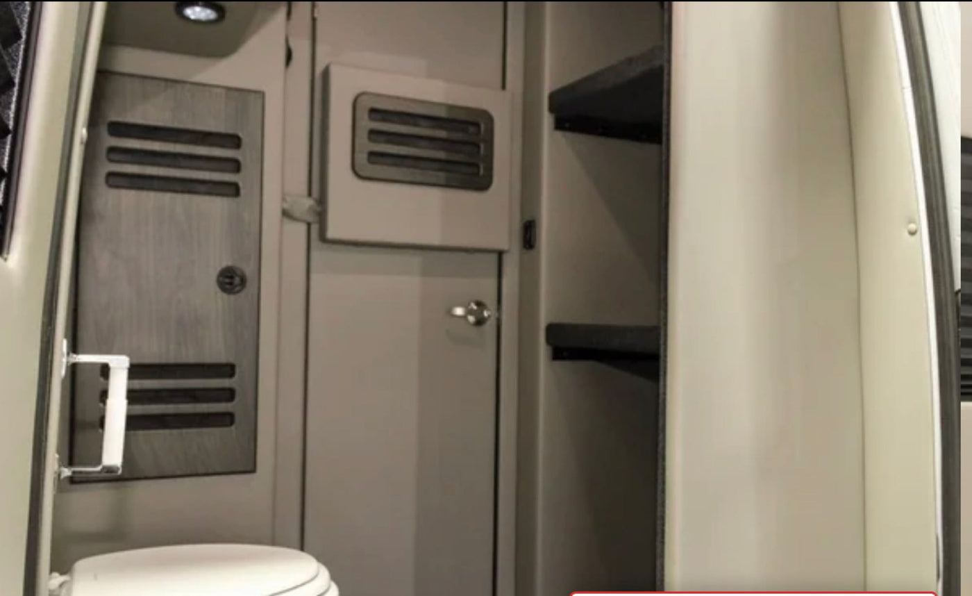 An RV rental's compact interior: showing a toilet, a light-colored wood-paneled wall with vents, and open storage shelves. — photo 20