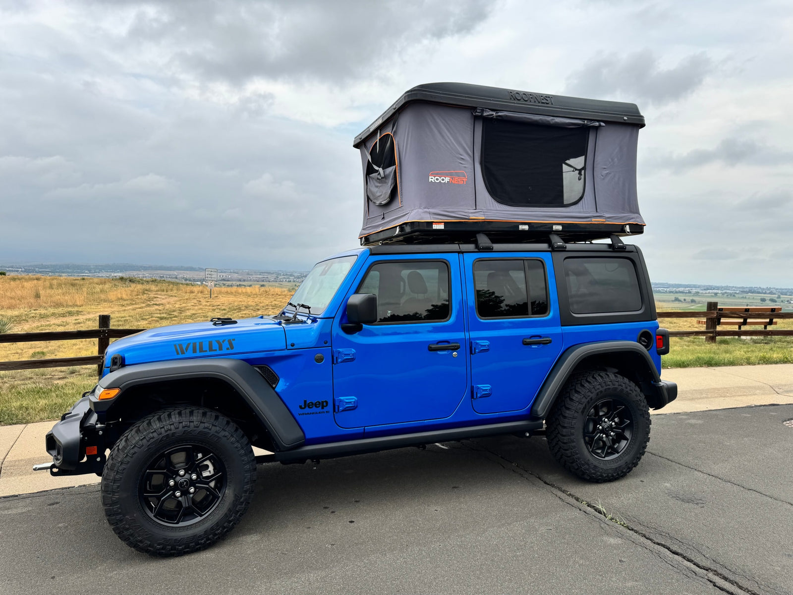 This blue Jeep Wrangler with a gray Roofnest rooftop tent is ideal for an RV rental camping adventure.