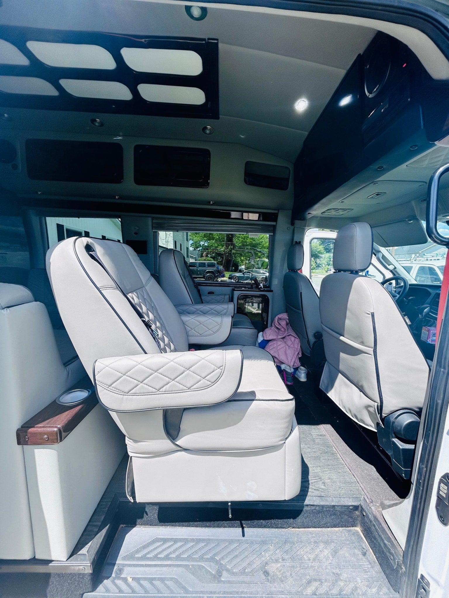 Spacious rv rental interior with luxurious grey captain's chairs, overhead storage, and bright lighting for comfortable travel.