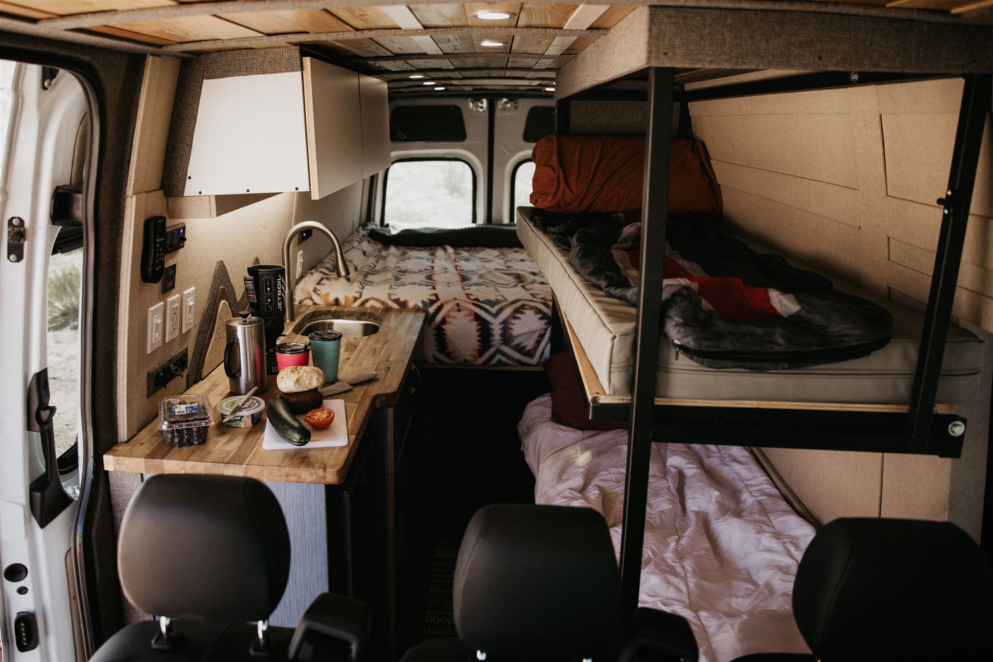 Explore this RV rental's comfy interior: kitchen, rear bed, & bunk. Ideal for campervan trips!
