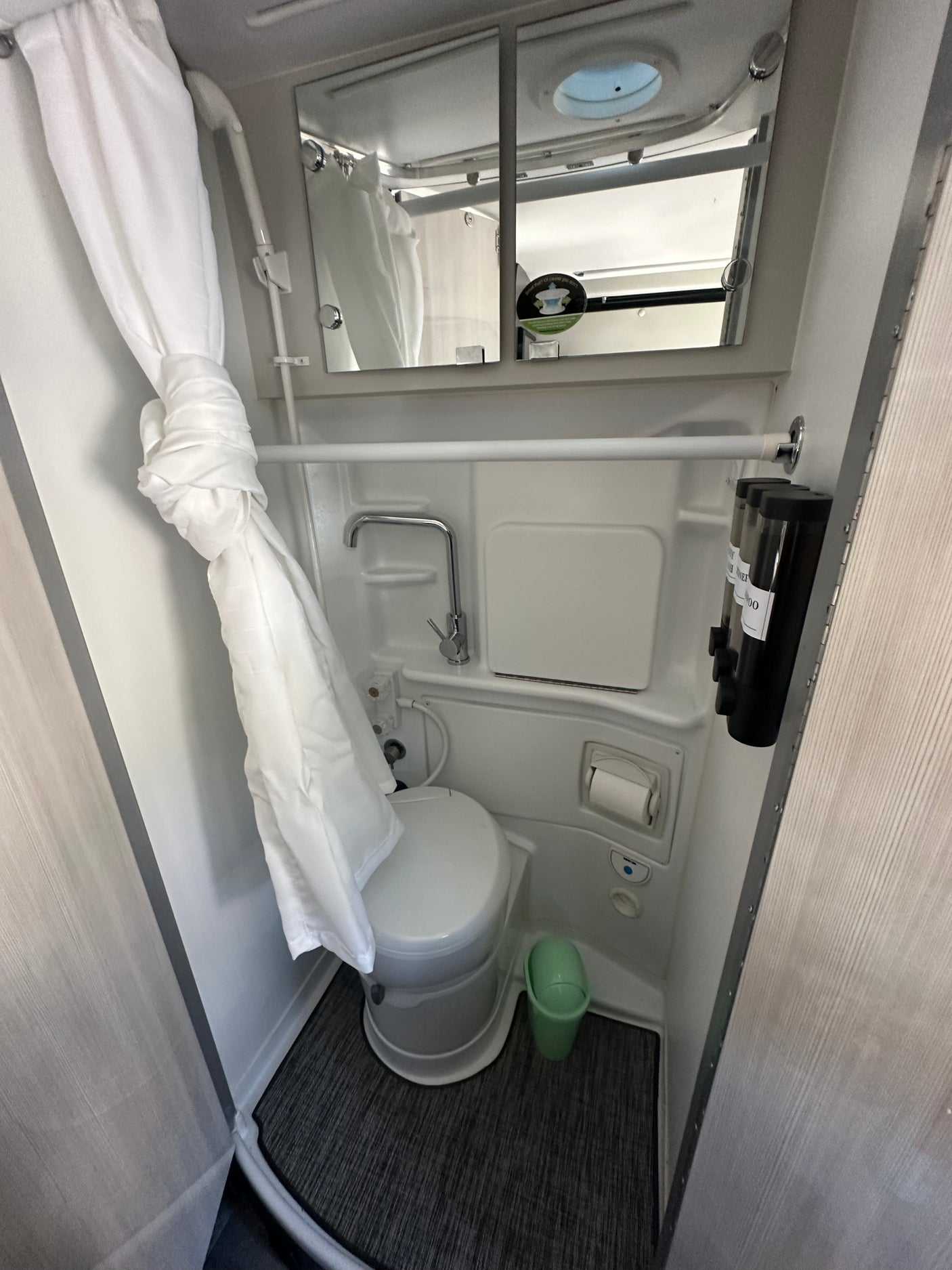 This RV rental features a full, compact bathroom with a toilet, shower, sink, and essential amenities.