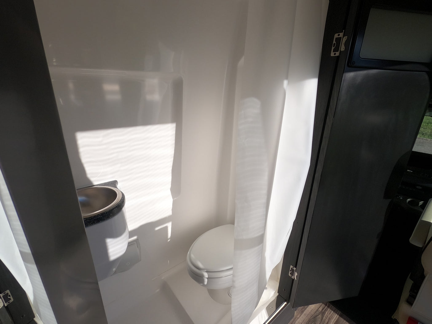 See this bright, compact RV rental bathroom with a toilet, sink, and shower curtain, ideal for travel convenience.