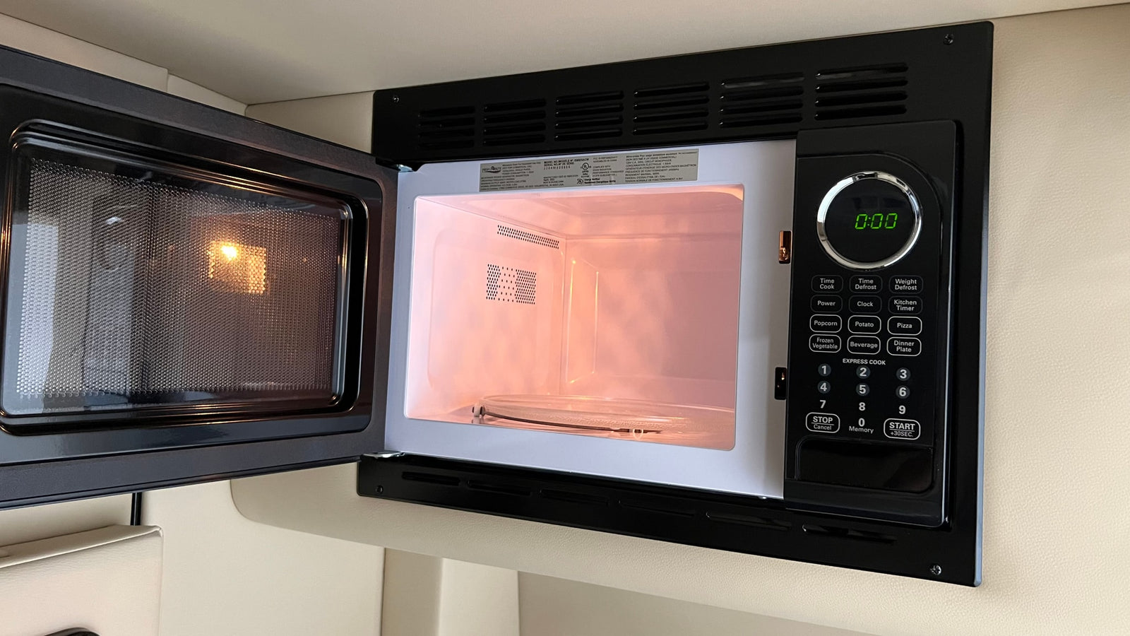 Open microwave in an RV rental kitchen, with its interior lit and display showing 0:00, ready for use.