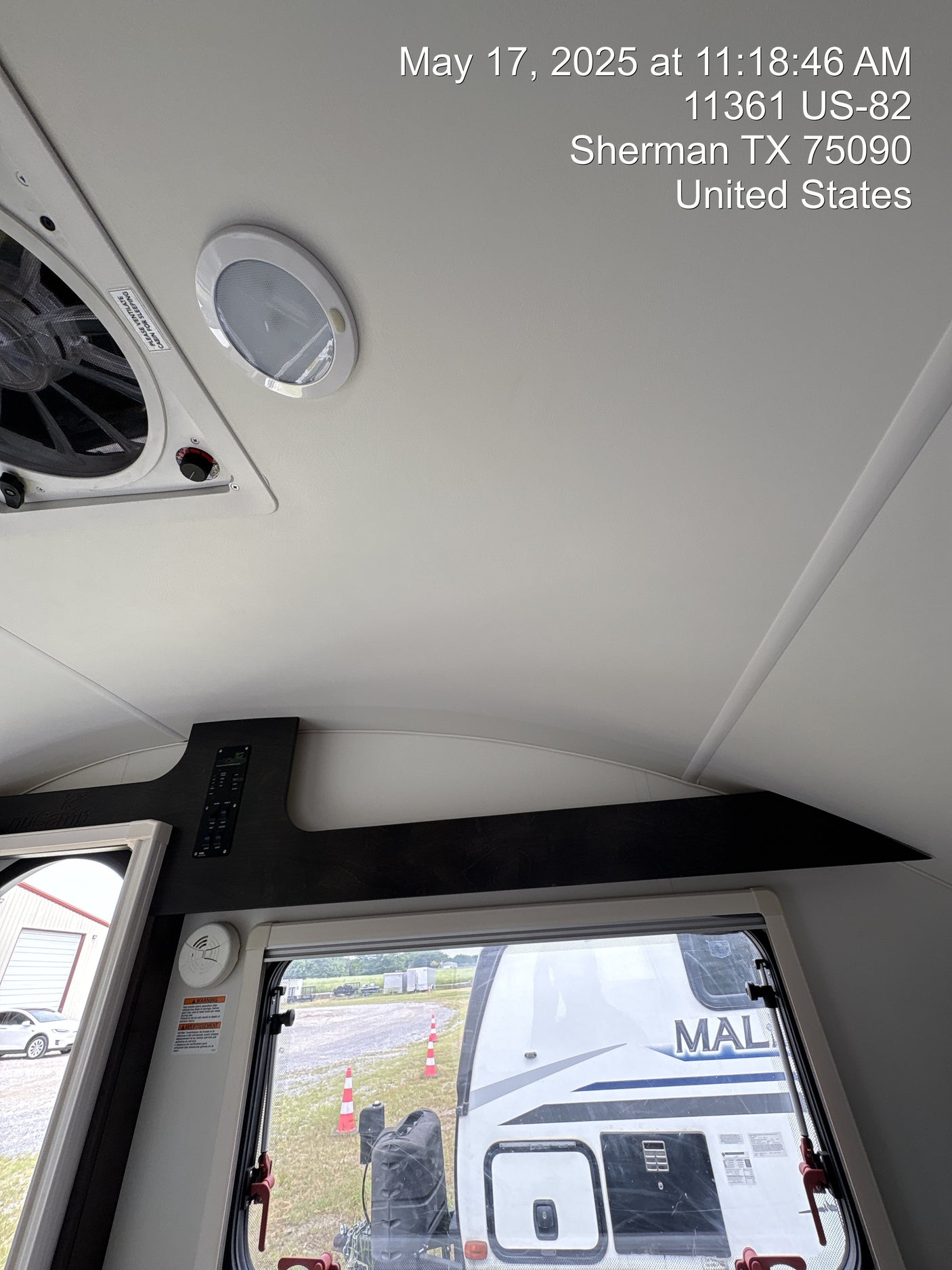 Inside an RV rental, showing overhead fan, light, controls, and an outside view of another RV through the window.