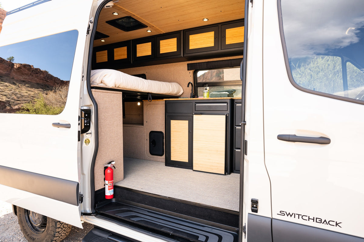 Step into this modern RV rental van conversion, featuring a cozy bed, full kitchen, and stylish wood accents, ready for desert adventures. — photo 5