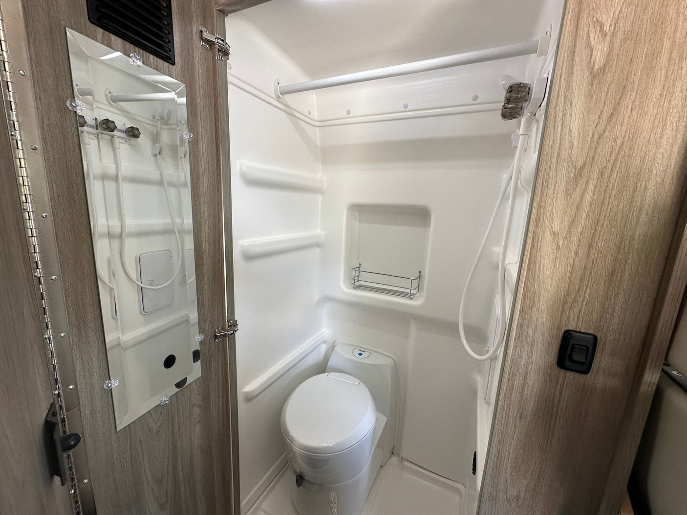 Inside an RV rental, this clean and compact bathroom includes a shower, toilet, and built-in storage for efficient use of space.